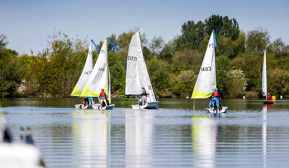 wide shot people sailing dinghies on a lake