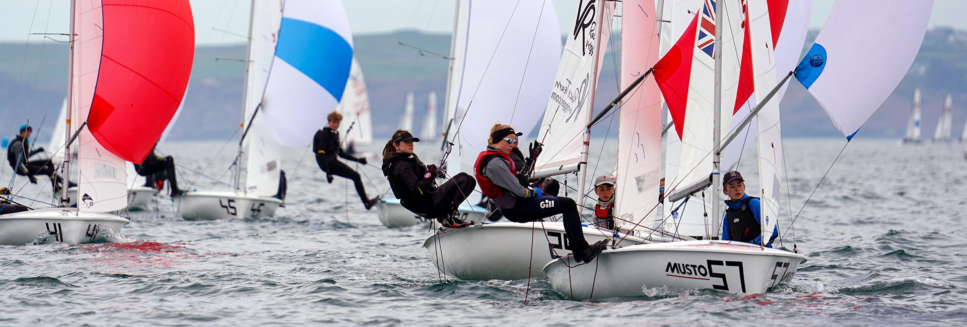 hero - wide shot of young people participating in a dinghy race on a larger body of water