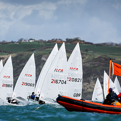 wide shot of dinghy race with race official in rib