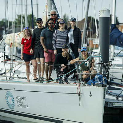 posed image of a group of 8 sailors standing on the front of a large yacht