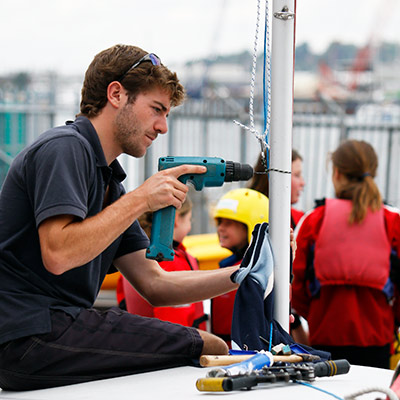 candid shot of volunteer repairing mast with electric drill