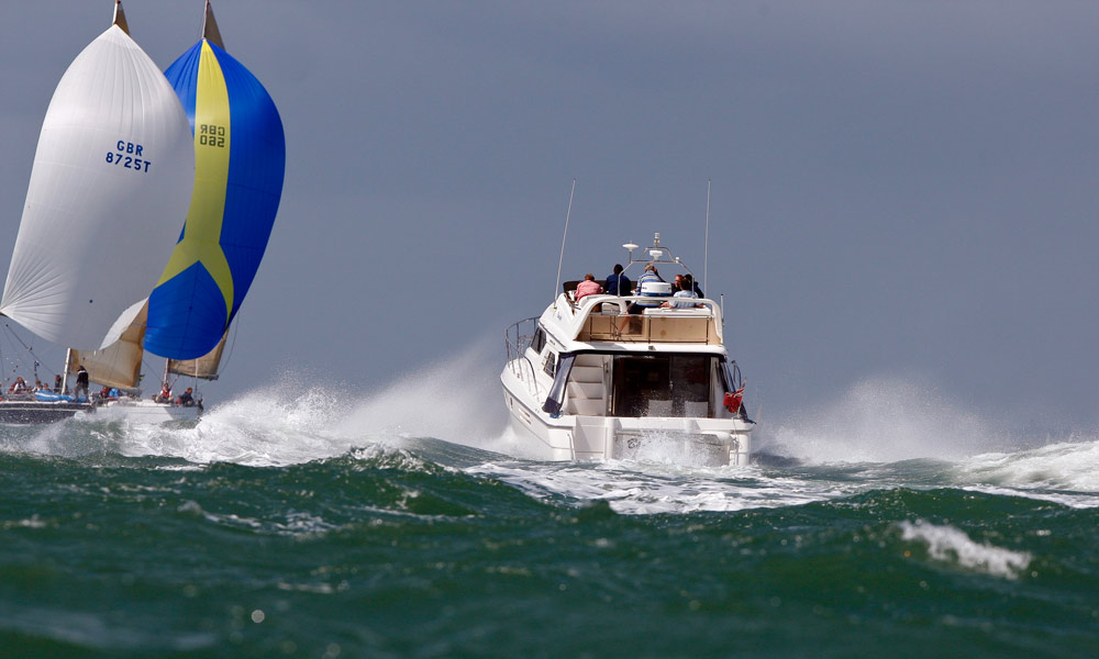 wide shot of motorboat approaching sail boat