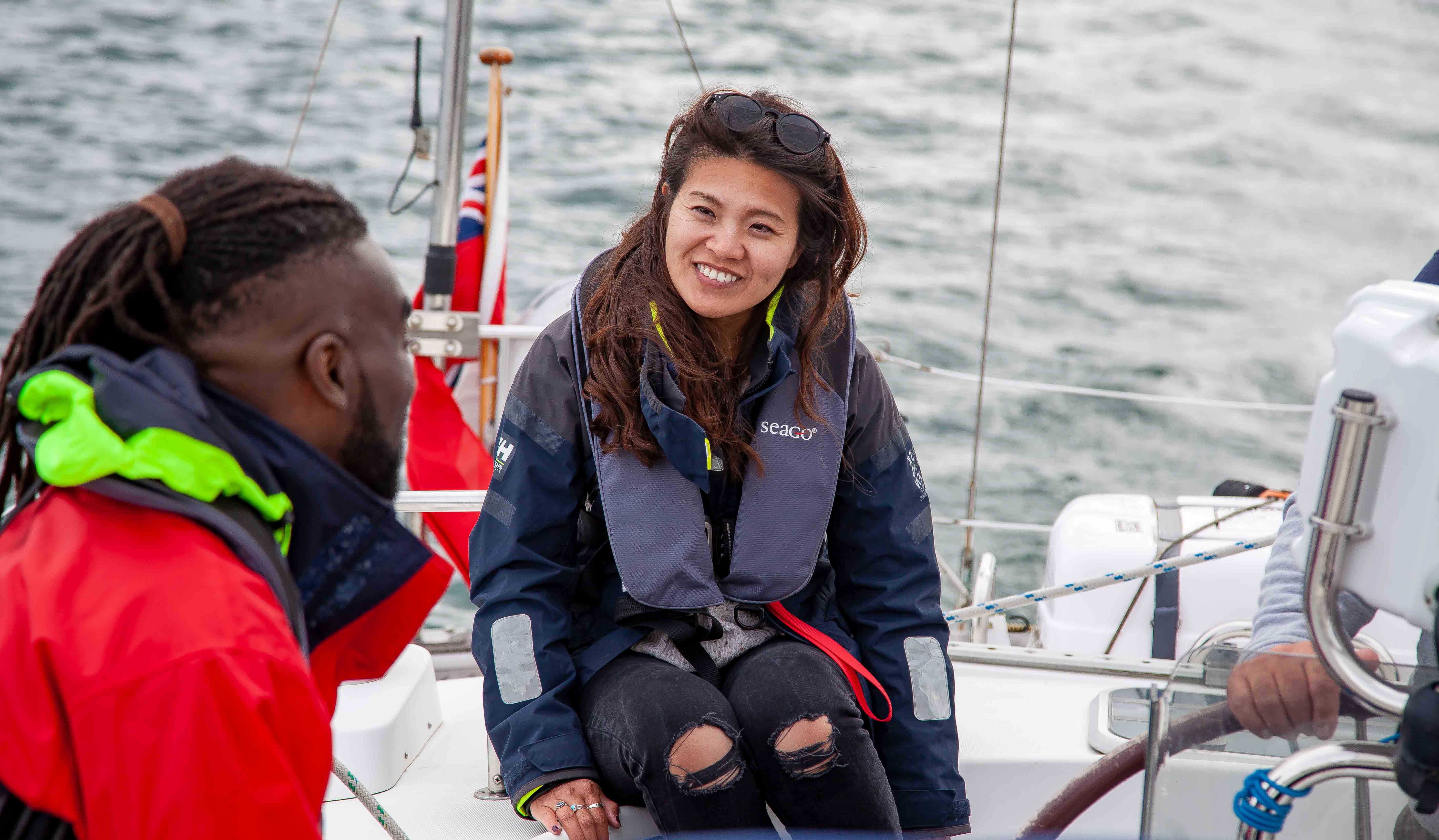 Wide shot of a instructor and sailor in lifejackets on a boat