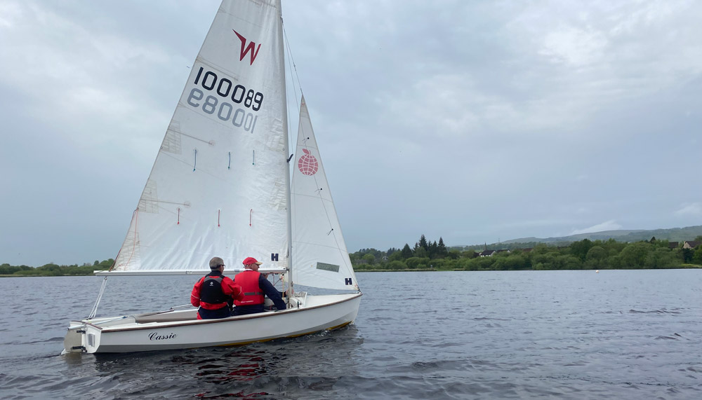 two people sailing a dinghy 