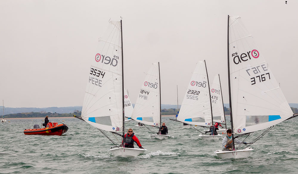 wide shot of a fleet of people in small dinghies 