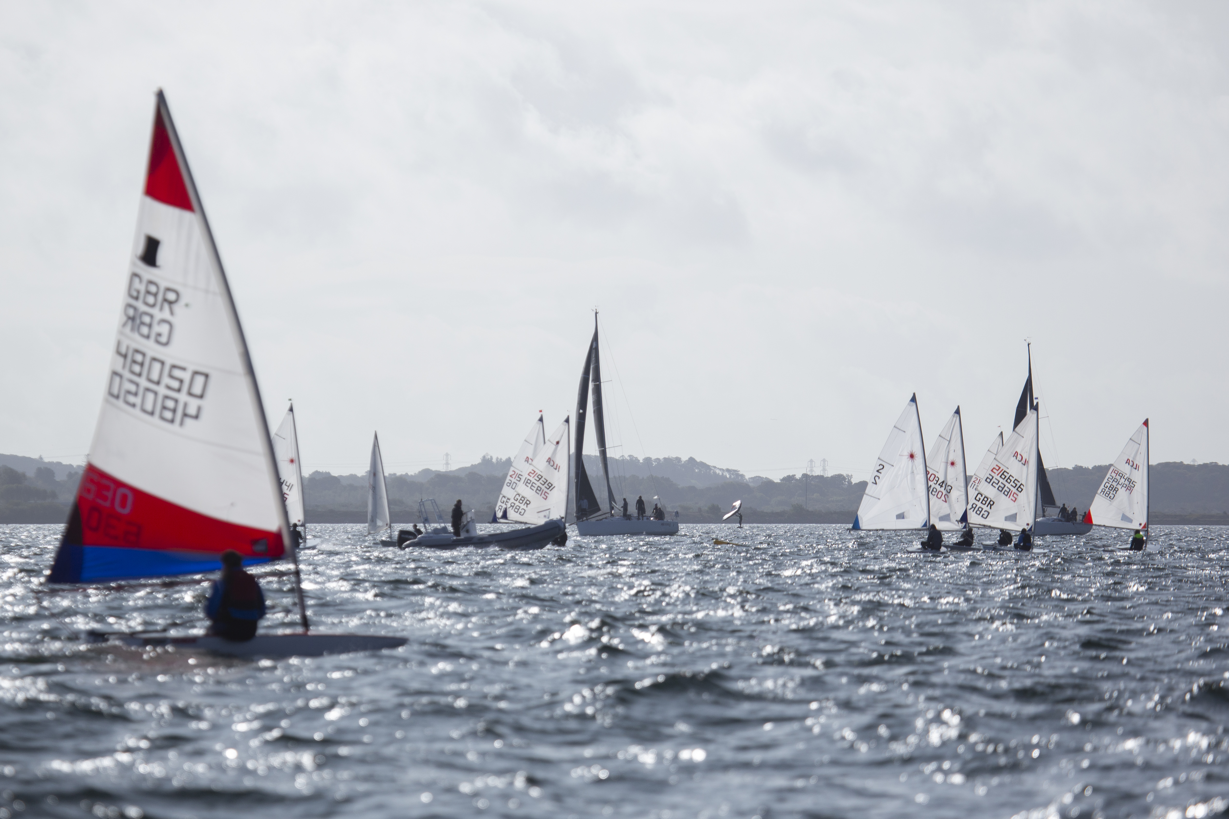 Images showing activity at the Giant Academy with coaches delivering race training in dinghies and Windsurfers ashore and afloat.