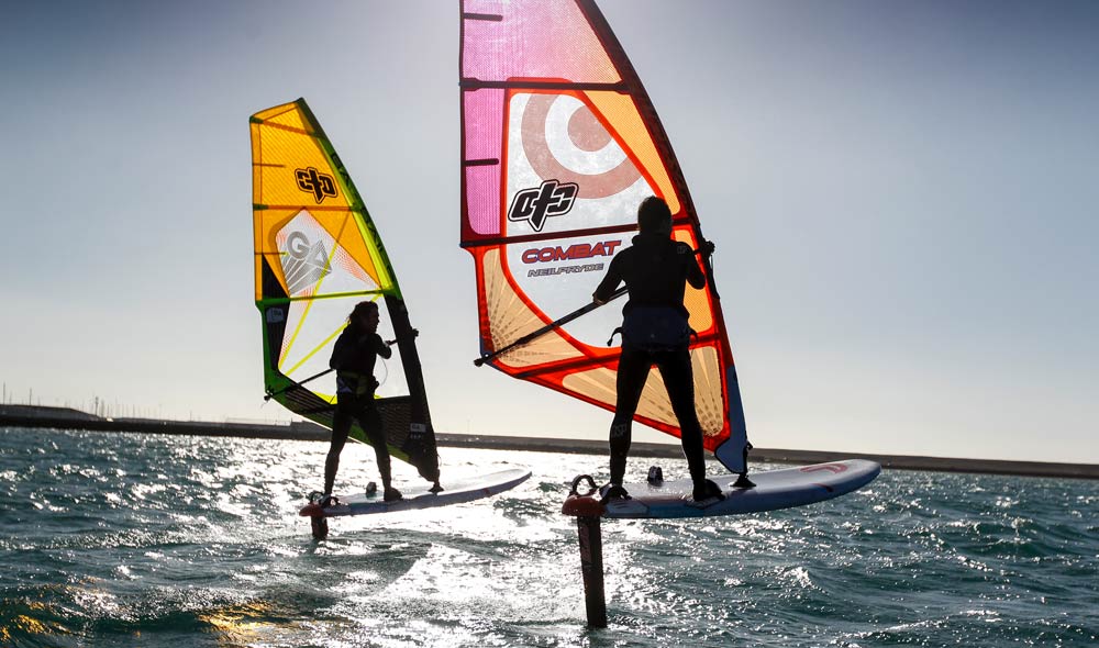 two people wind surfing at sunset