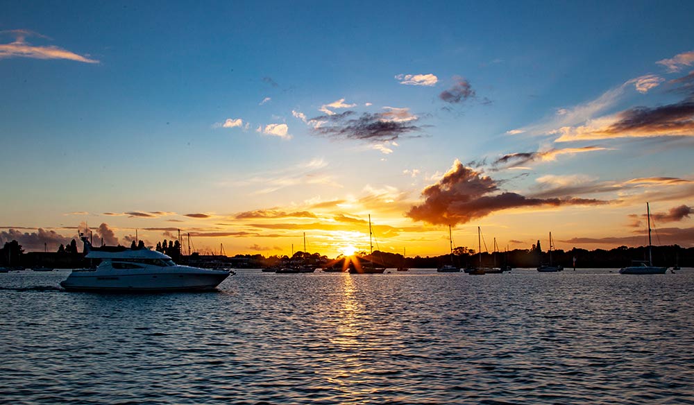 shot of boat sailing on the water from dawn to dusk 