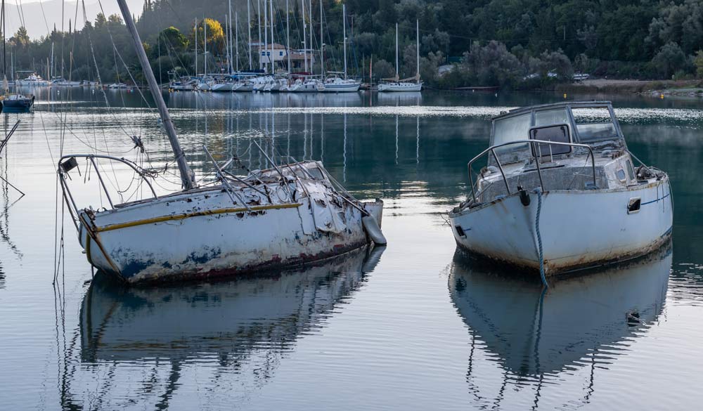 Broken derelict sailing boats in shallow waters.