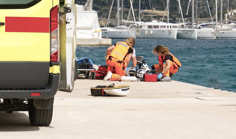 Ambulance workers provide first aid to a person in a yacht port.