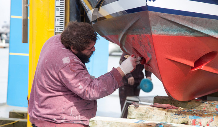 closeup of man painting bottom of boat is protective coating