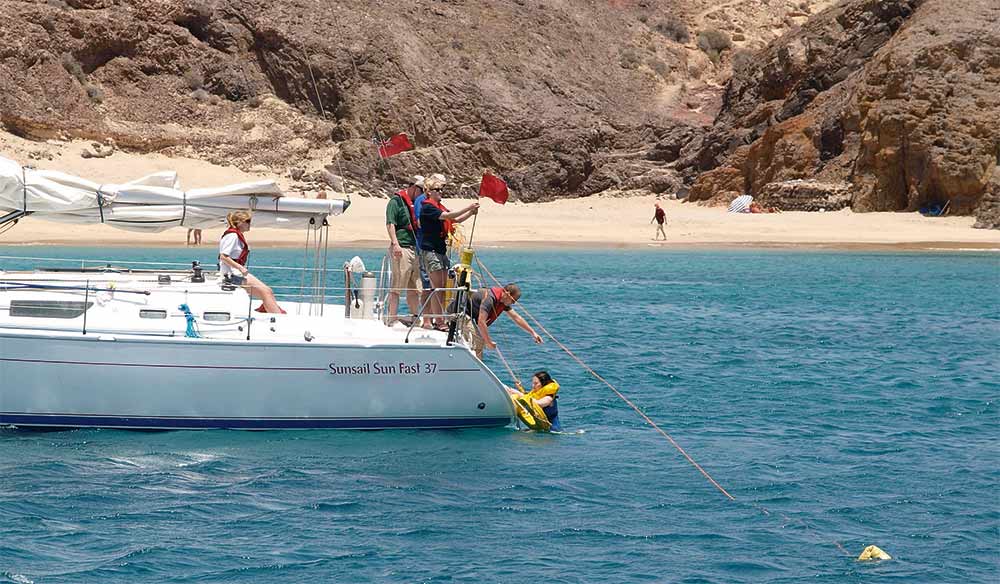 demonstrating how to help someone out on water off side of yacht