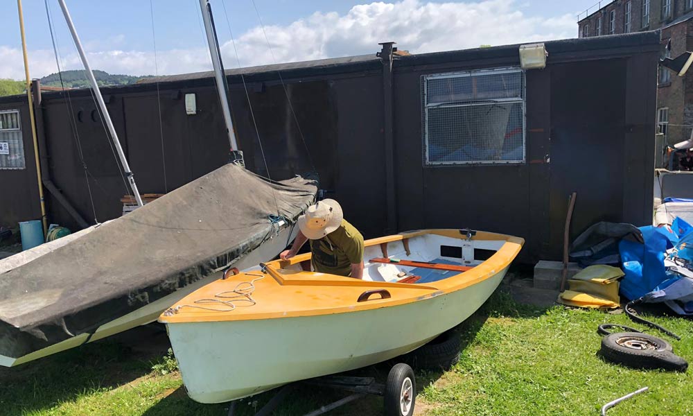 man restoring an abandoned dinghy 