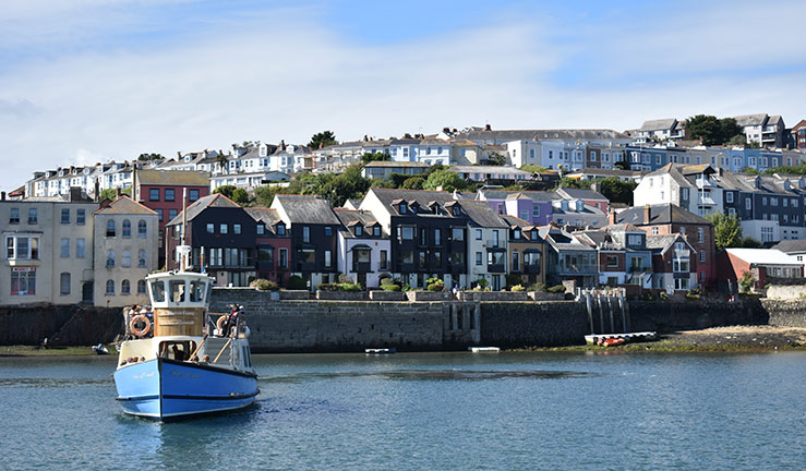 Wide shot of ferry boat with Cornish fishing village Falmouth in the background. 