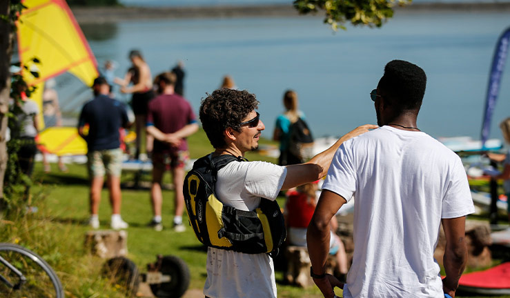 People socialising on the shore of a lake