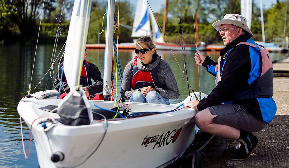 candid shot of a volunteers helping two sailors in a sailing dinghy