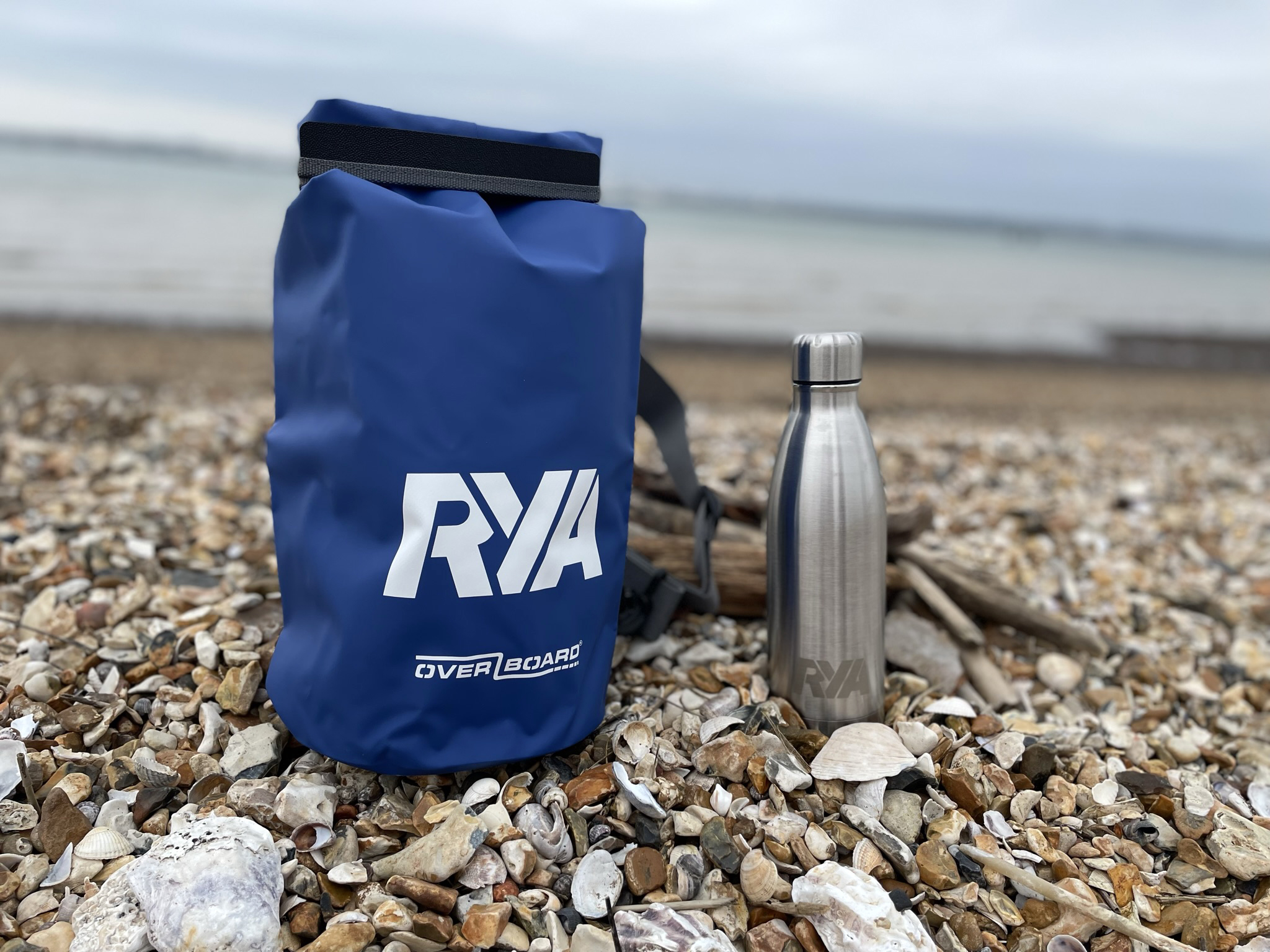 RYA overboard dry bag and RYA water bottle sat on the beach