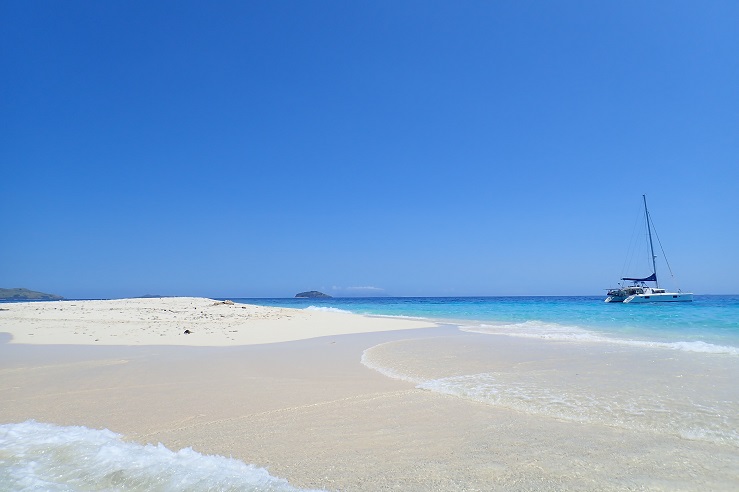 A catamaran is anchored off a desert island in the Yasawas, Fiji 