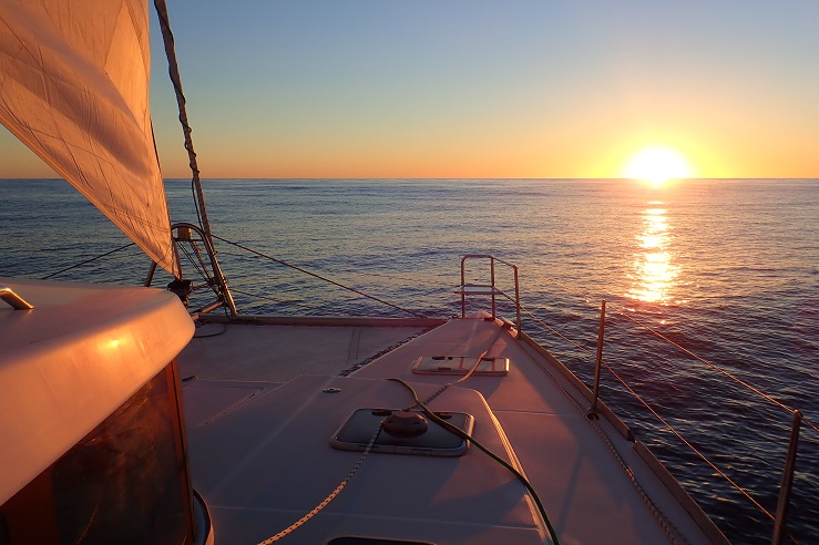 A catamaran sails towards the sunset