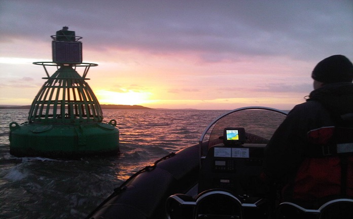 Motor boat approaching beacon at night