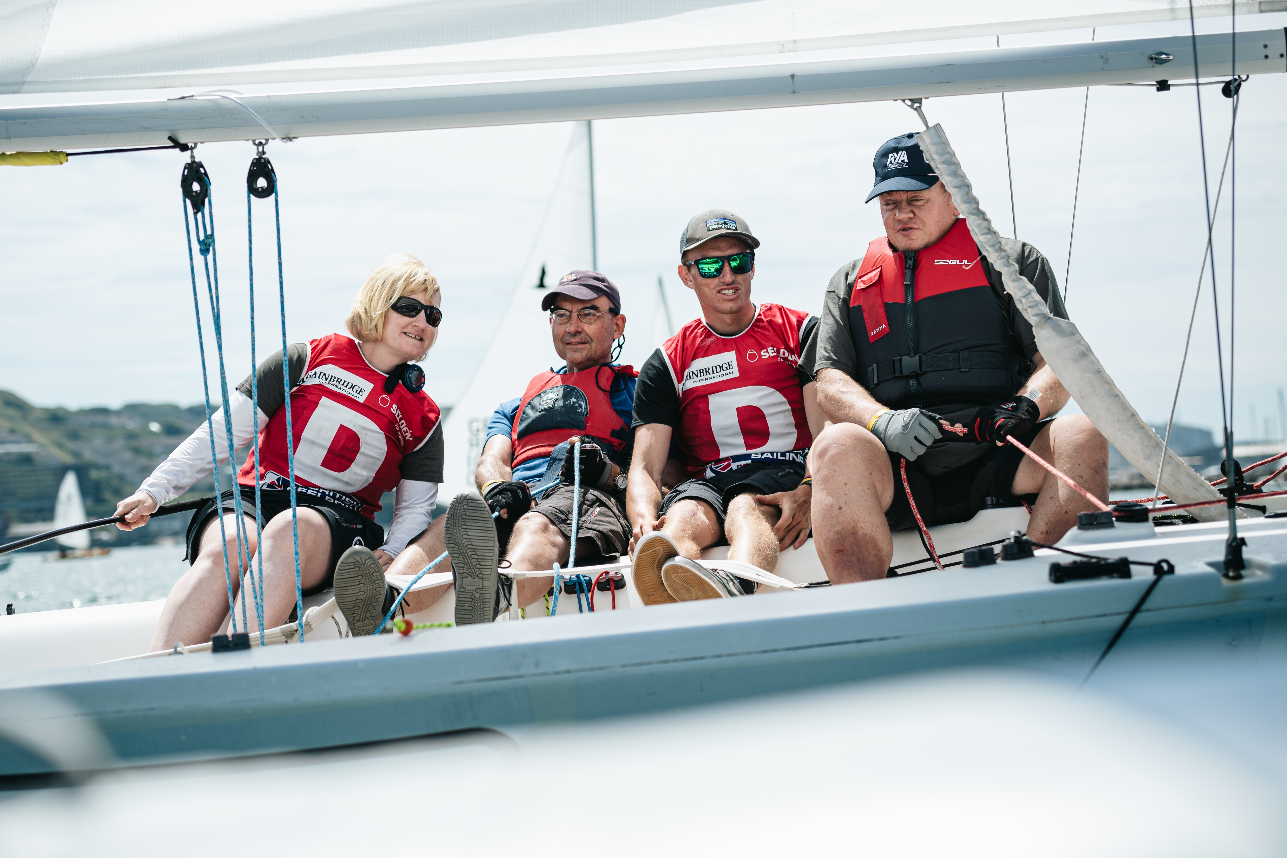 3 visually impaired sailors, with a sighted crew, racing a small keelboat on a sunny day