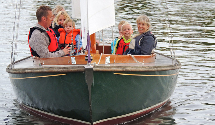 mid shot of a family sitting in a sailing boat