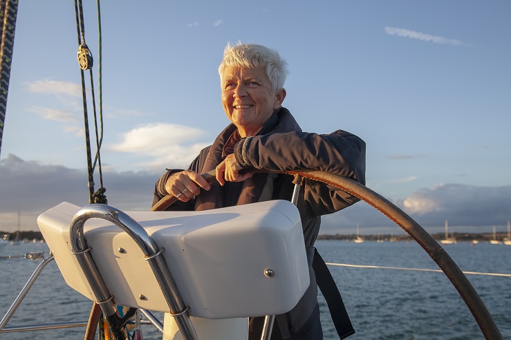 Lady stands smiling at the helm of a boat