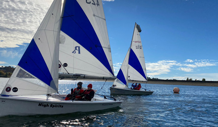 2 RS ventures racing towards camera. Water is calm and the sailors are wrapped up in gloves and hats. 