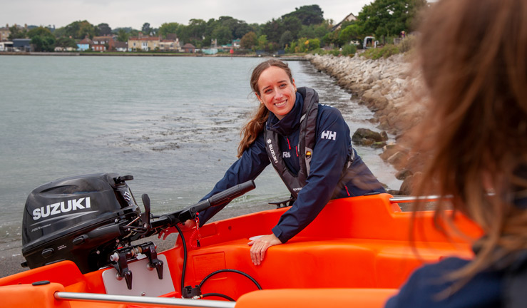 Suzuki confirmed as RYA Dinghy and Watersports Show 2023 sponsors. Woman setting outboard on safety boat. 