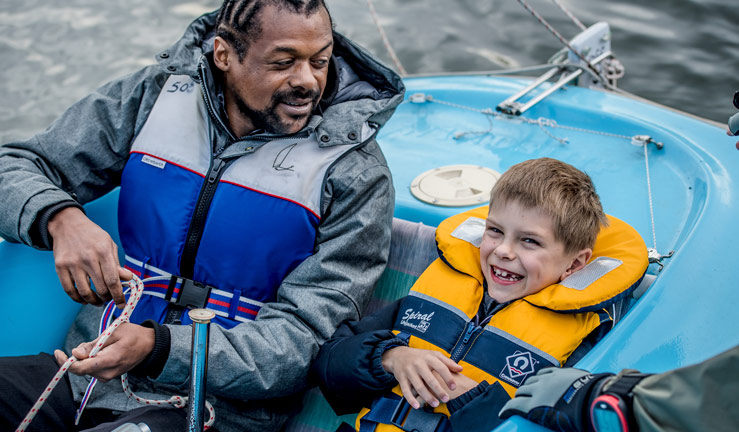 Man and boy smiling in sailing dinghy