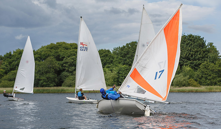 wide shot of 3 sailors sailing dinghies 