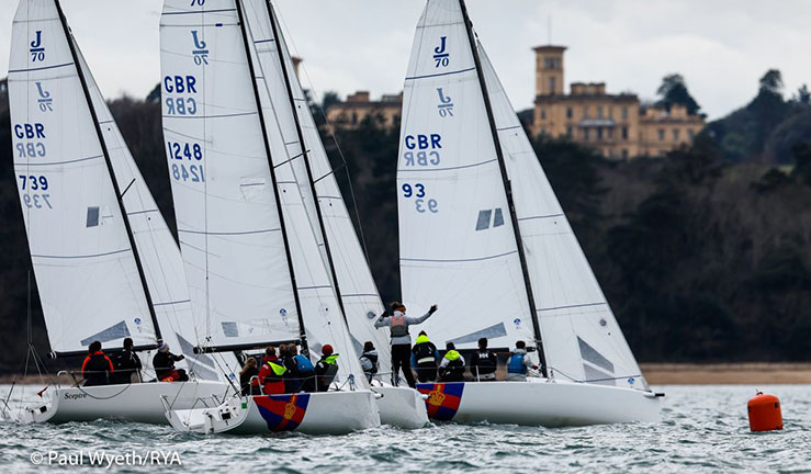 Four J70 keelboats crewed by the British Keelboat Academy racing upwind with Osborne House on the Isle of Wight in the background.