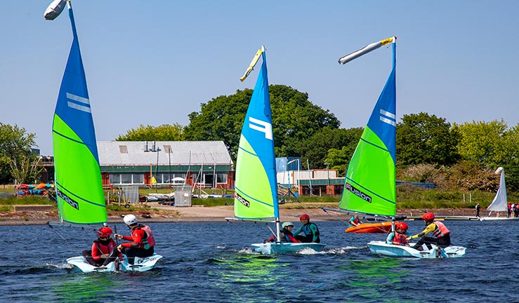Three boats sailing in front of a clubhouse