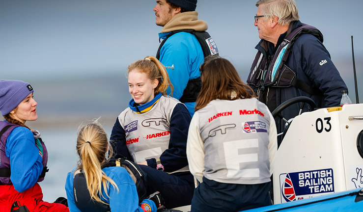 Four young female match racers sat on a blue RIB between races wit the coaches at the RYA Marlow Ropes Women's Match Racing Champs.