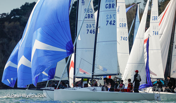 Fleet of J70s racing downwind with blue spinakers flying during a British Keelboat Academy training weekend.