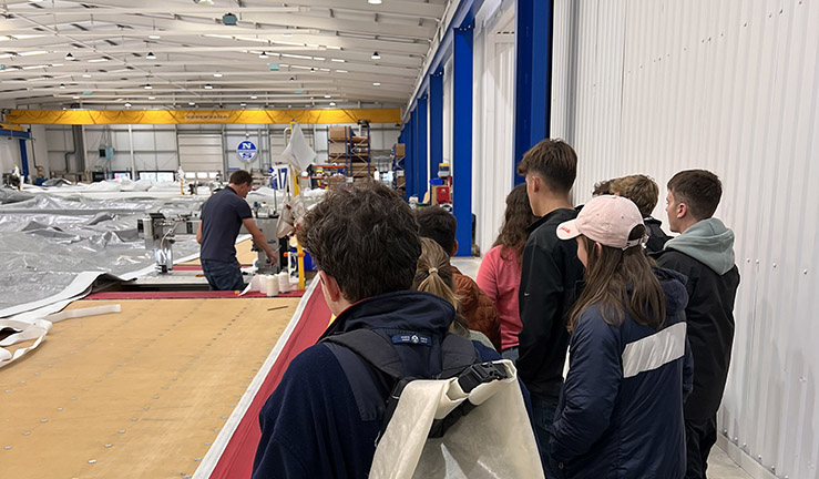 Group of would-be British Keelboat Academy recruits looking on during sailmaking activity in loft at North Sails.