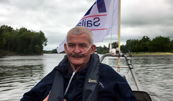 posed shot of Marty Ansfield on motor boat with Sailability flag