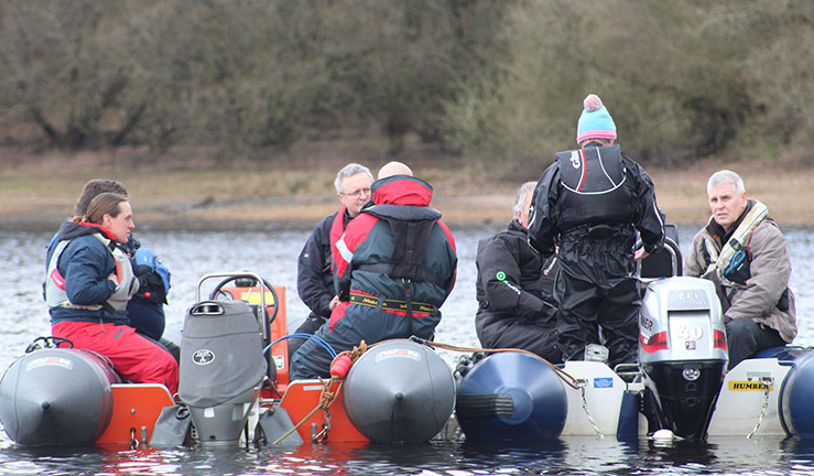 Two RIBS on a grey day, each with three people aboard, side by side on the water during North region powerboat Course.