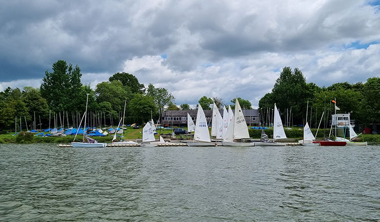 View from the water of Banbury Sailing Club and boats with sails up. 