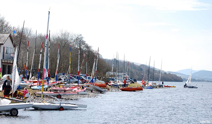 Lots of colourful dinghies on the shore at Bala Sailing Club with mountains on the skyline.