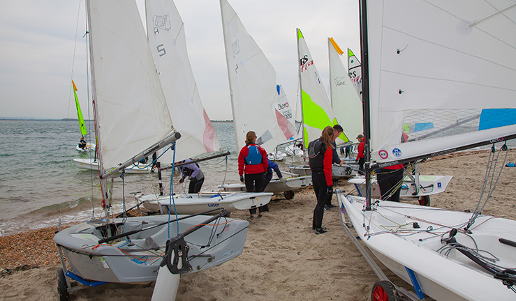 candid shot of young people on the beach prepping dinghies before going out on the the water