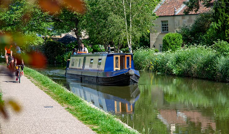 wide shot of a blue canal boat on an inland waterway on a beautiful sunny day