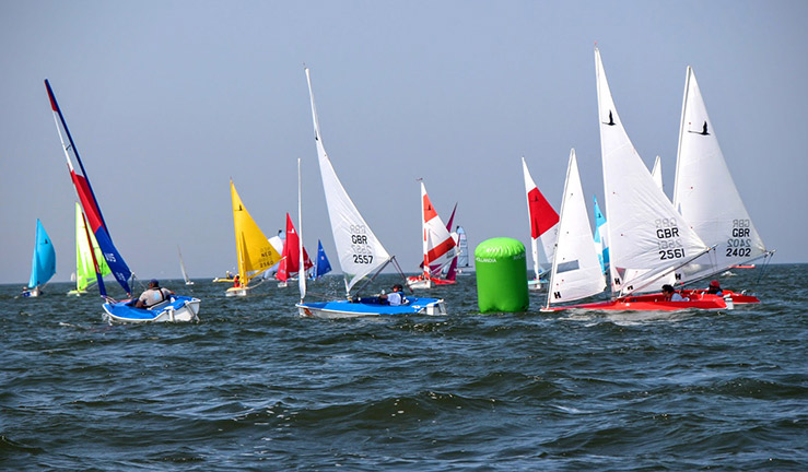 wide shot of a fleet of racing para-sailors in dinghies on the open water