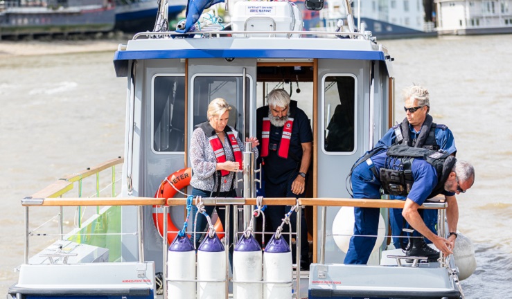 Baroness Vere standing at the back of a motorboat talking with crew