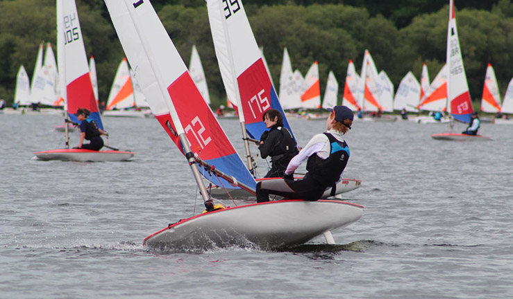 Topper sailor racing in the foreground with variety of other colourful junior dinghy classes in the background at the Regional Junior Championships, Bassenthwaite 2023. 