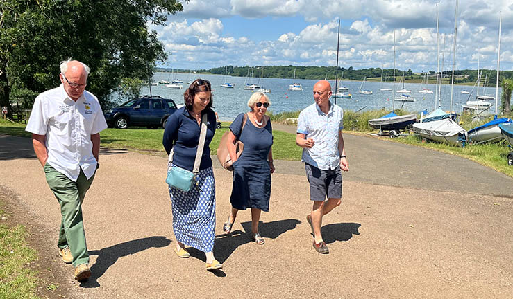 Four people walking through the boatpark on a sunny day at Rutland SC, including RYA CEO Sara Sutcliffe, Regional Chair Judy Lambourne and Commodore Nick Neve.