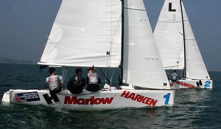 Two teams match racing Elliott 6M keelboats upwind on a sunny day at the Harken RYA Youth Match Racing Champs at Weymouth & Portland National Sailing Academy, 2021 