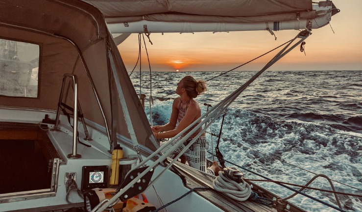 Meg on her yacht on the open sea with the sunset behind her