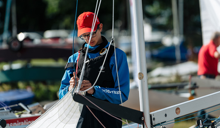 candid shot of young man tying sale to rigging