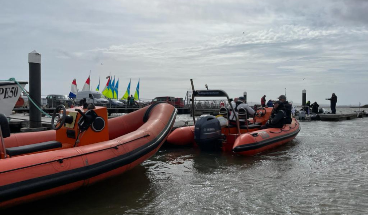 RIBs by a pontoon with people aboard and dinghies in the background